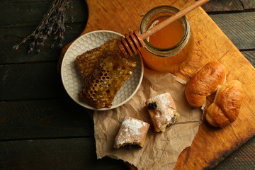 Honeycombs on plate, hot buns on wooden background