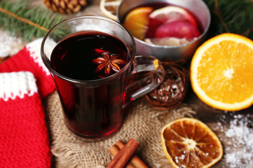 Christmas composition of mulled wine, cinnamon, pine and red knitted mittens on wooden background