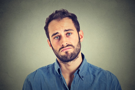 Portrait of a sad young man isolated on gray wall background