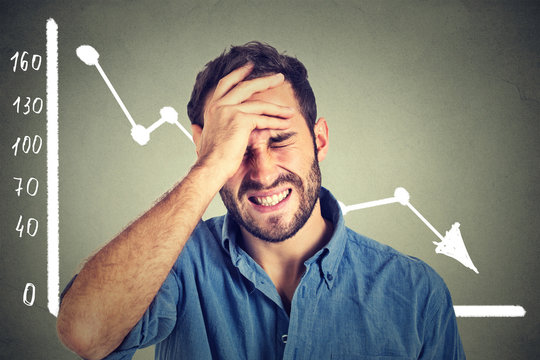 frustrated stressed young man desperate with financial market chart graphic going down