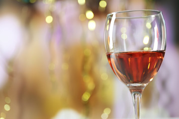 A glass of pink wine on blurred lighted background