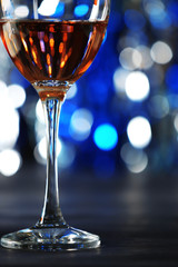 A glass of pink wine on blurred lighted background