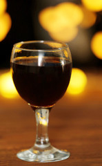 A glass of red wine on blurred lighted background