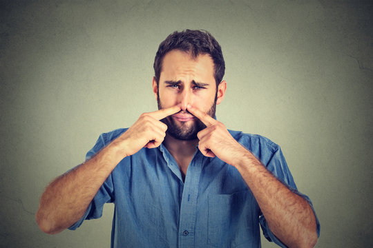 disgusted man pinches nose with fingers hands looks with disgust something stinks