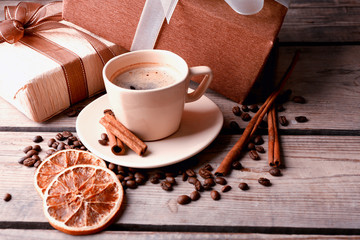 Beautiful gift, cup with coffee and coffee grains on wooden background