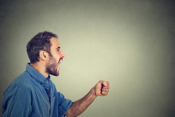 ngry young man screaming with fist up in air