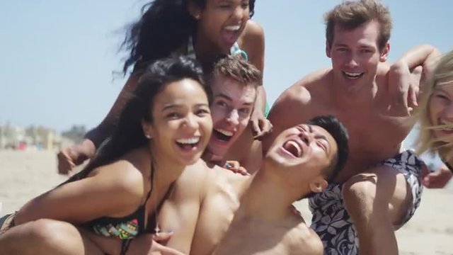 Healthy young group of multi ethnic friends smiling at camera on the beach