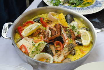 seafood paella being cooked in a silver frying pan
