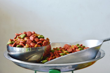 dog food in stainless bowl and iron scoop on weighing scale