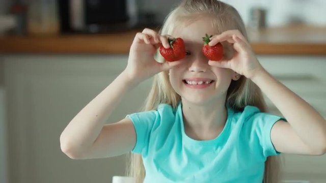 Laughing girl with two strawberries dabbles