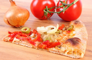 Slice of vegetarian pizza, tomatoes and onion on wooden surface