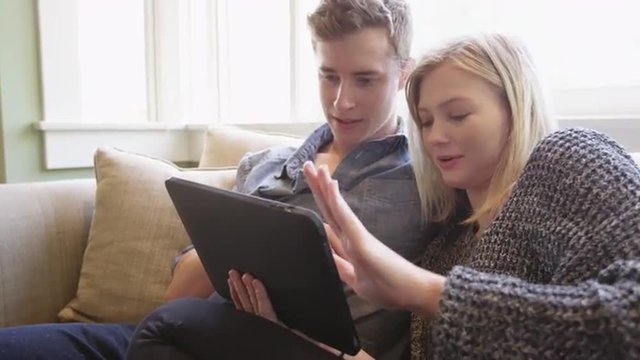 Cute couple using tablet together on couch