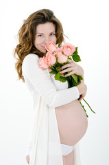 young pregnant woman with delicate roses in hands. Romantic pregnancy on a white background 
