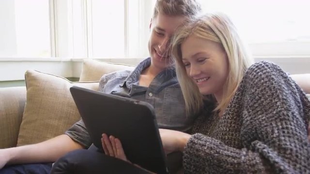 Beautiful couple using tablet together on couch
