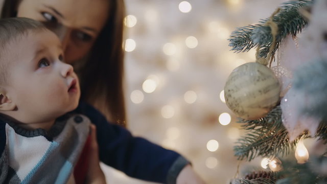 Mother decorating christmas tree with her baby