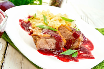 Duck breast with plum sauce and cabbage in plate on green napkin