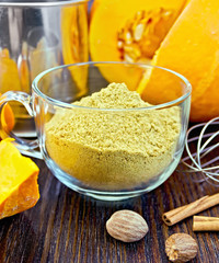 Flour pumpkin in glass cup with sieve and cinnamon on board