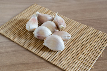 garlic cloves on makisu mat on wood texture