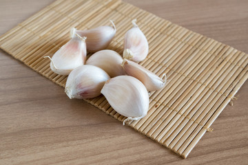 garlic cloves on makisu mat on wood texture
