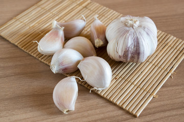 garlic cloves on makisu mat on wood texture