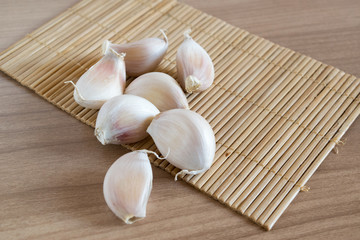 garlic cloves on makisu mat on wood texture