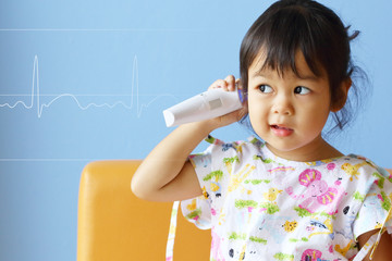 Asian Little Girl Measures Her temperature on Blue Background with Heart Beats Cardiogram.