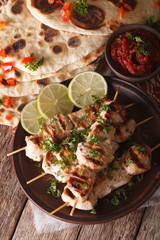 Chicken tikka skewers and naan flat bread with chutney closeup. vertical
