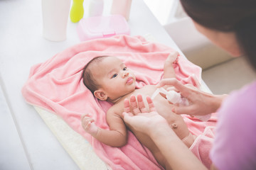 Obraz na płótnie Canvas woman applying baby lotion to her baby