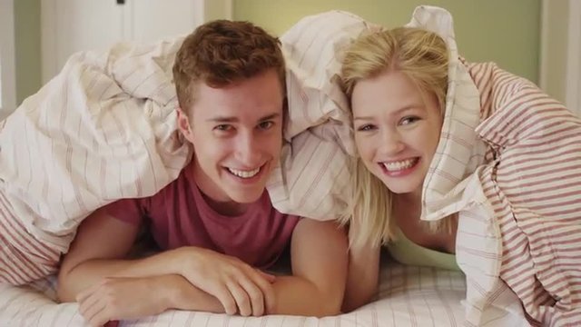 Young couple smiling under the covers