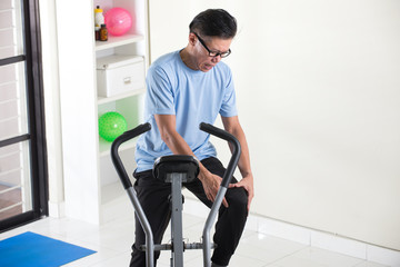 Fototapeta na wymiar asian senior male knee pain on exercise bike