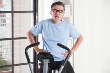 Fototapeta na wymiar asian senior male panting heavily on exercise bike