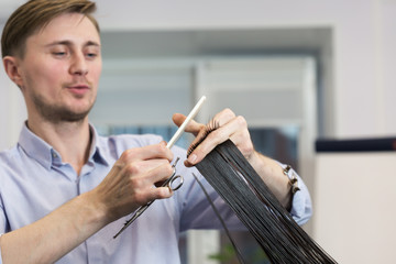 Obraz na płótnie Canvas Handsome hairdresser making haircut of a brunette female client