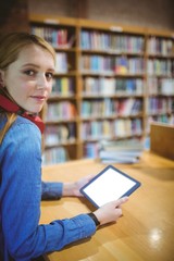 Pretty student with headphones using tablet in library