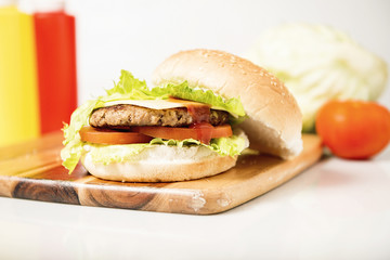 Hamburger with cheese and ingredients with a white background and timber board.