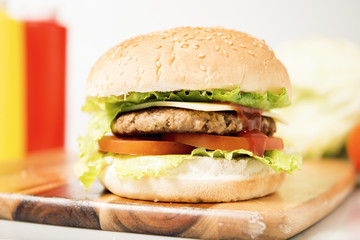 Hamburger with cheese and ingredients with a white background and timber board.