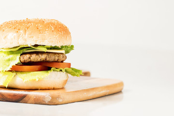 Hamburger with cheese and ingredients with a white background and timber board.