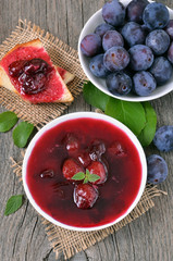 Plum jam in bowl on wooden table