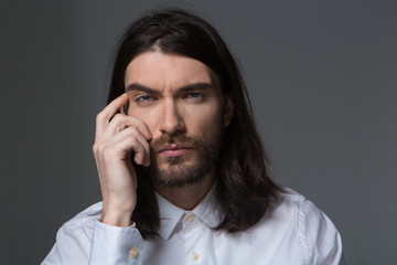 Pensive man with beard and long hair looking at camera