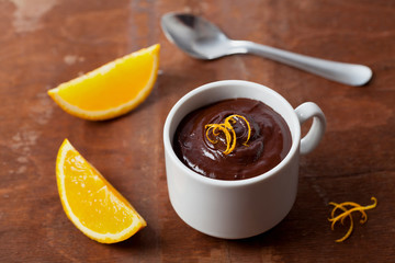 Delicious dessert from dark chocolate mousse with orange slice decorated citrus peel on vintage table