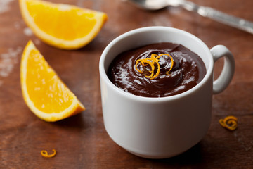 Delicious dessert from dark chocolate mousse with orange slice decorated citrus peel on rustic table