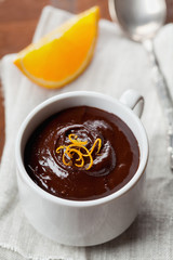 Delicious dessert from dark chocolate mousse with orange slice decorated citrus peel on rustic table