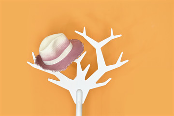 Clothes hanger with hat on orange background