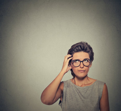 Confused thinking woman in glasses bewildered scratching her head