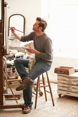 Male Artist Working On Painting In Studio