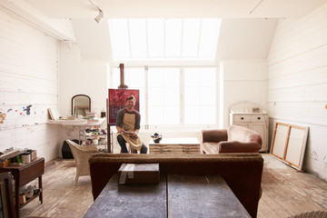Male Artist Working On Painting In Bright Daylight Studio