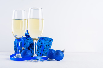 Glasses of champagne and gifts on white background