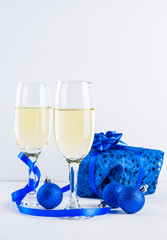 Glasses of champagne and gifts on white background