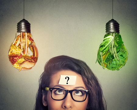 Woman thinking looking at junk food and vegetables shaped as light bulb