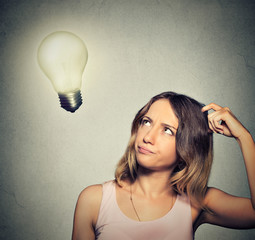 girl thinks looking up at bright light bulb