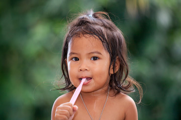 Child asian little girl brushing teeth on green background